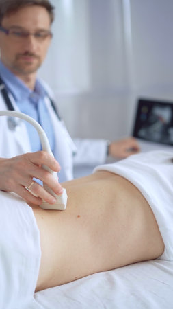 Doctor man is using ultrasound equipment on the back of a patient, woman. The results are on a monitor in the background. Medicine service conceptの写真素材