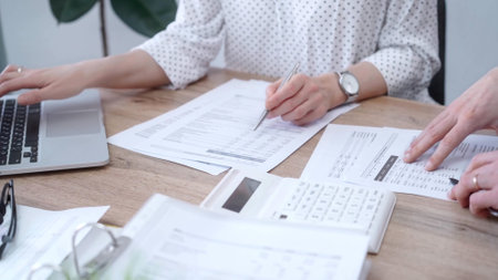 Business people professionals analyzing financial documents. Two colleagues working together, reviewing papers and using a laptop. Finance audit and taxesの写真素材