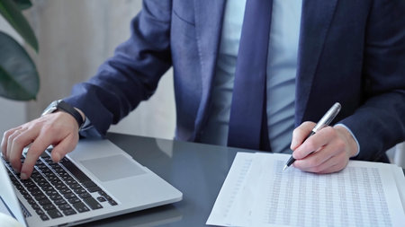 Businessman analyzing financial data on laptop and calculator. Close-up of a professional auditor...