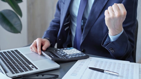 Businessman analyzing financial data on laptop and calculator. Close-up of a professional auditor working on financial reports. Business conceptの写真素材