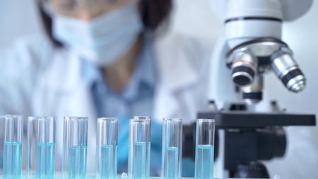Test tubes with a blurred scientist in a lab coat in the background