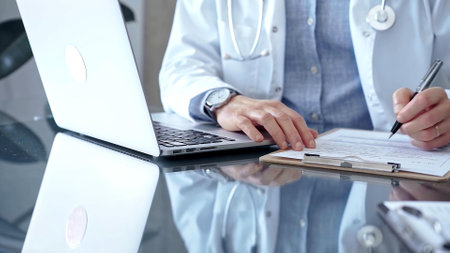 Doctor writing medical records on a glass desk with laptop. Medicine and Health Careの写真素材