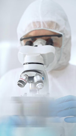 Scientist in ppe analyzing samples and analyzing samples with a microscope in a laboratory setting