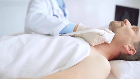 Doctor woman wearing white medical gloves performing neck ultrasound exam on male patient. Medicine...