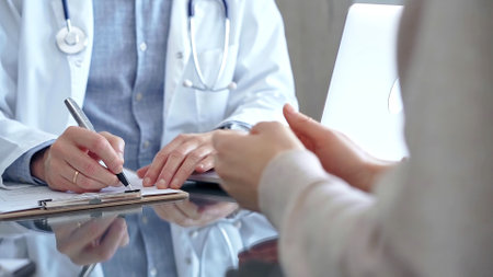 Doctor man is making notes while consulting patient with clipboard and a pen in his hand in medical office. Trust concept in Medicineの写真素材