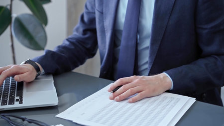 Businessman analyzing financial data on laptop and calculator. Close-up of a professional auditor...