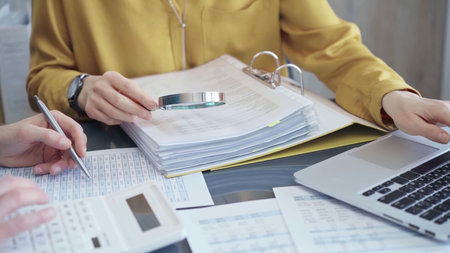 Business colleagues reviewing financial documents and calculating taxes. Auditor inspecting...