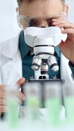Man scientist with protective glasses using microscope in laboratory. Microbiology science concept