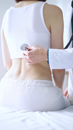 Doctor and patient. Physician is using stethoscope examining woman lungs from the back side. Medicine and health careの写真素材