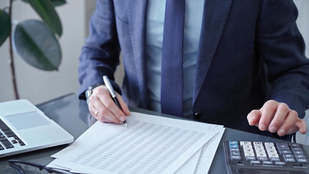 Businessman analyzing financial data on laptop and calculator. Close-up of a professional auditor...