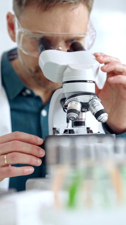 Man scientist with protective glasses using microscope in laboratory. Microbiology science conceptの写真素材