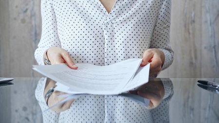 Auditor woman analyzing financial documents with magnifying glass and calculator at her office desk in formal dark blue blouse. Business people conceptの写真素材
