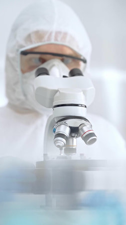 Scientist in ppe analyzing samples and analyzing samples with a microscope in a laboratory setting