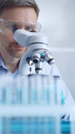 Man scientist with protective glasses and gloves is using microsの写真素材