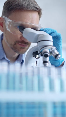 Man scientist with protective glasses and gloves is using micros