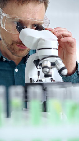 Man scientist with protective glasses using microscope in laboratory. Microbiology science conceptの写真素材