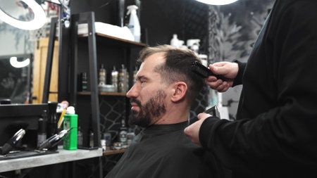 Professional barber trimming clients hair with precision, wielding scissors and comb inside contemporary grooming salonの写真素材