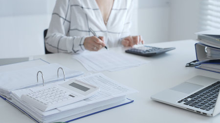 Calculator on financial documents, with an accountant taking notes, emphasizing accounting, finance,...
