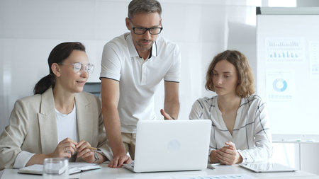 Business team collaborating and analyzing data on a laptop during a productive meeting in a modern...