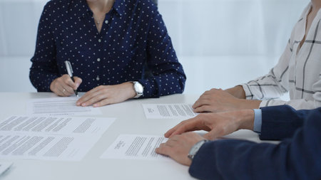 Business woman signing contract during a meeting with partners in contemporary office