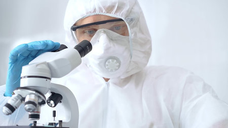 Scientist in ppe analyzing samples using a microscope in a laboratory setting. Close-up of a focused...