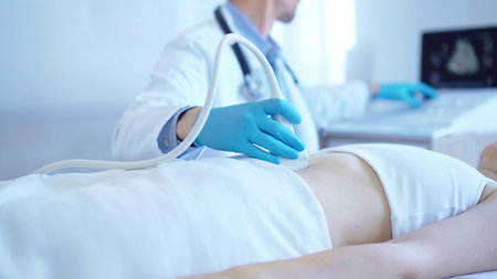 Doctor man wearing a blue medical gloves using an ultrasound equipment on a female patient lying...