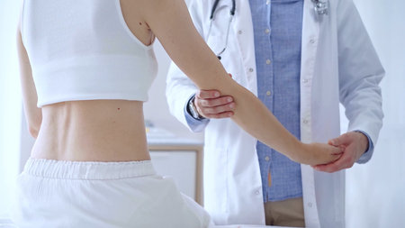 Doctor man examines a patients elbow during a medical consultat