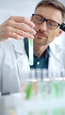 Scientist examining lab tube with a green fluid. Microbiology and science concept
