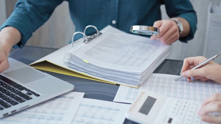 Business colleagues reviewing financial documents and calculating taxes. Auditor inspecting...