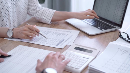 Professional female bookkeeper or auditor are working on business finances with a colleague, using...