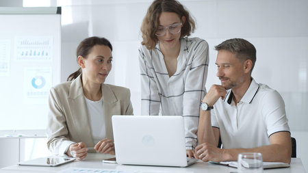 Business people team collaborating and analyzing data on a laptop during a productive meeting in a...