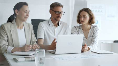 Business people team collaborating on a project, analyzing data on a laptop during a productive...