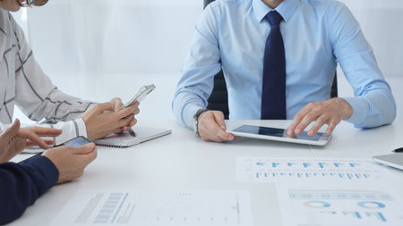 Business colleagues strategizing in modern workspace, reviewing financial analytics on digital...