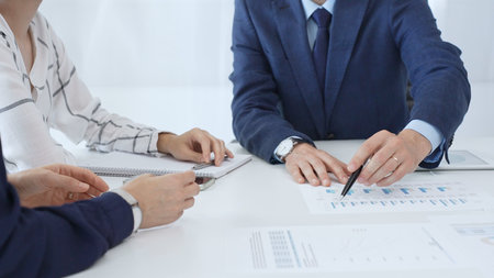 Business people engaging in a corporate meeting, discussing strategies while analyzing financial...
