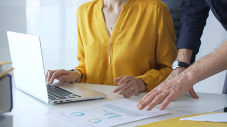 Professional team reviewing financial data on laptop, analyzing charts and strategizing corporate...