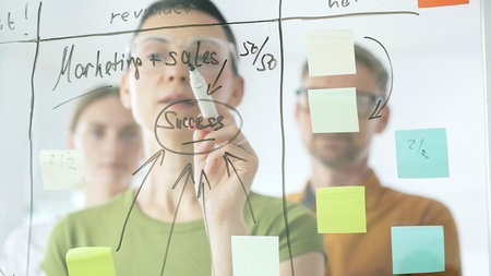 Marketing team collaborating, strategizing business growth with colorful sticky notes on transparent...