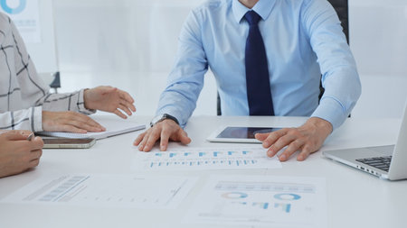 Business people analyzing financial charts, graphs on tablet and laptop, collaborating closely...