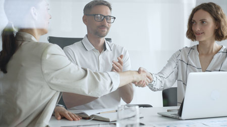 Businesswomen partners are shaking hands after successful negotiation, colleagues clapping,...