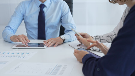 Business team working together, analyzing financial charts and data on digital tablet and...