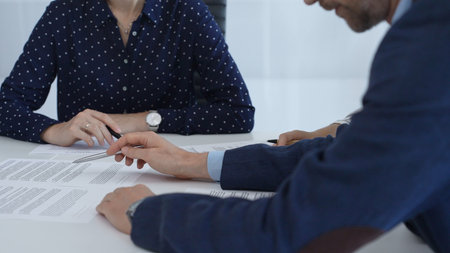Corporate professionals analyzing contract details, gesturing toward key points while negotiating partnership terms in modern office boardroomの写真素材