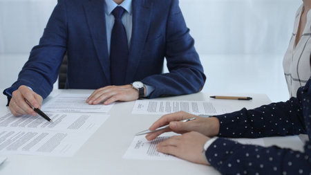 Business people reviewing contract during a meeting, pointing at specific clauses and discussing...