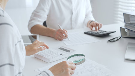 Groupe of accountants collaborating on financial analysis, using a magnifying glass, calculator, and laptop to ensure data accuracy. Audit and taxesの写真素材
