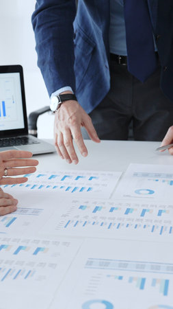 Businessman standing above the table and pointing into financial charts while discussing financial data, market trends during a corporate meeting in office. Business people conceptの写真素材