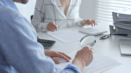 Groupe of accounting professionals analyzing financial documents, checking spreadsheet details with calculator and magnifying glass. Audit and taxes conceptの写真素材
