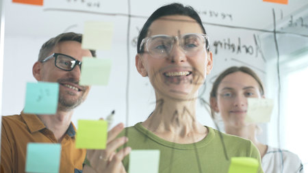 Business people team brainstorming strategic goals, mapping innovative concepts on transparent...