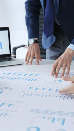 Business professionals analyzing financial data and market trends during a corporate meeting,...