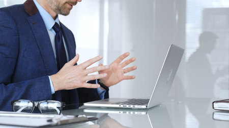 Businessman having a video conference, gesturing during an online business meeting or remote...