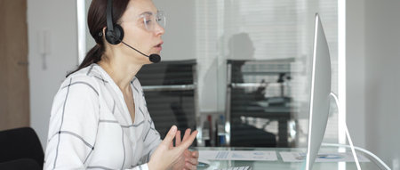 Woman working in call center, providing customer support through headset, communicating in virtual...