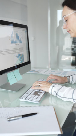 Woman analyst working on computer, analyzing business data with charts and graphs, marketing report...