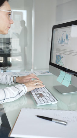 Woman analyst working on computer, analyzing business data with charts and graphs, marketing report on screen. Businesspeople conceptの写真素材